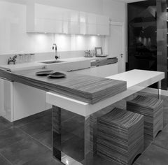 Modern kitchen interior featuring sleek white cabinets, a striped table island, and stylish stools.