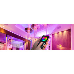Z-Wave RGBW LED-ohjain kätkössä, käsi käyttää kaukosäädintä värivalojen hallintaan.
