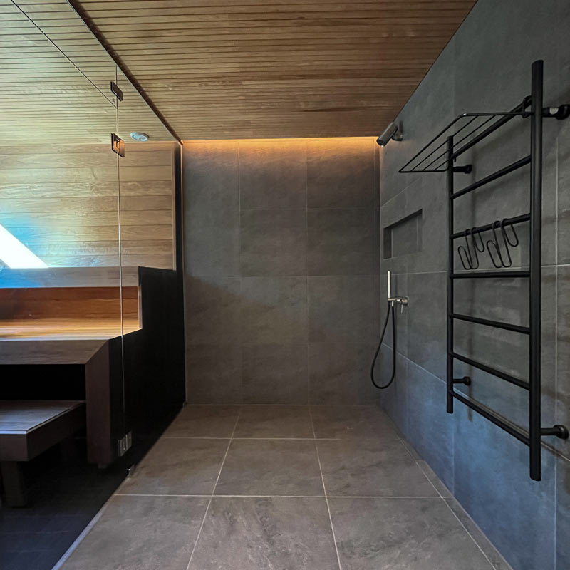 Moderni sauna, jossa on tyylikäs valaistus ja musta pyyhekuivaaja, täydellinen ostopaikka SAUNA LED-valonauha 24V IP65:lle.