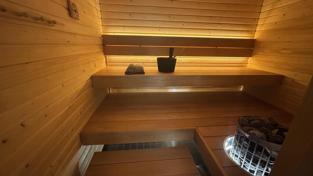 Pisteetön sauna LED-valonauha valaisee modernia saunaa, jossa puupinnat ja löylykiulu.